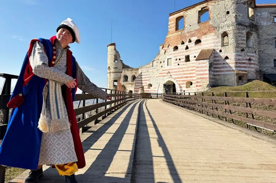 Pracownik muzeum w kostiumie nawiązującym do stylu sarmatyzmu przed Zamkiem w Janowcu zapraszający do zwiedzania muzeum